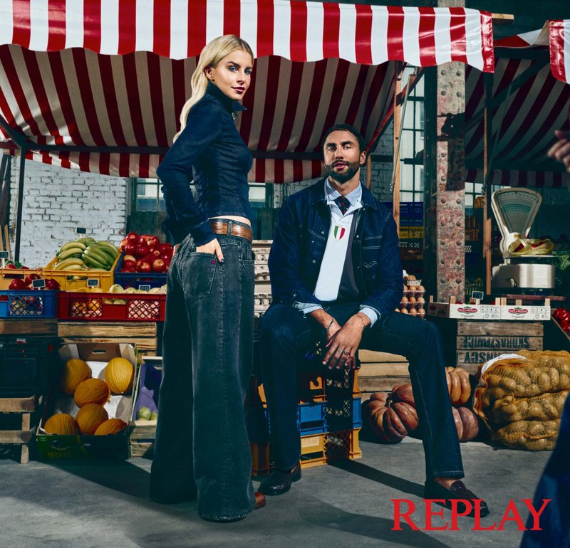 Outfit in jeans di tonalità scure; la donna indossa una camicia aderente e pantaloni a gamba larga, mentre l'uomo adotta un look a strati con una polo.