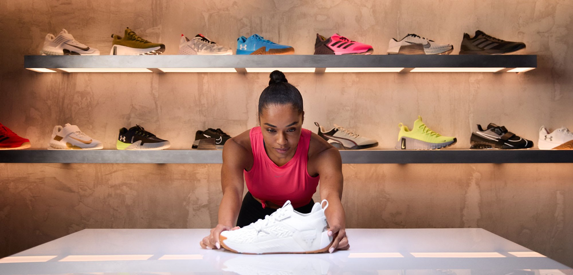 Weißer Sportschuh mit strukturiertem Seitenpanel und Gummisohle, auf einem Tisch präsentiert. Der Hintergrund zeigt verschiedene bunte Turnschuhe auf Regalen.