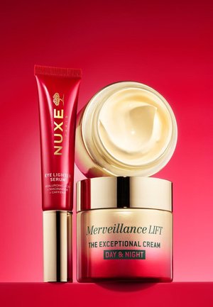 Deux produits de soin de la peau : un tube brillant de sérum illuminateur pour les yeux rouge et un pot de crème avec un couvercle doré, tous deux sur un fond rouge.