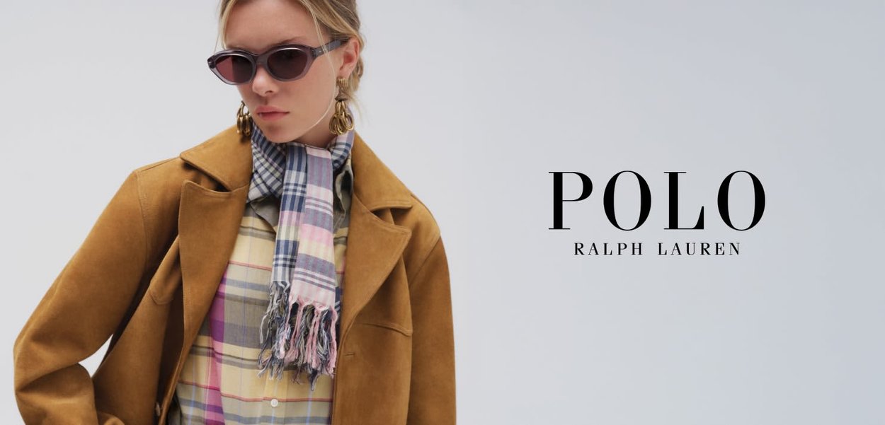 Vrouw met een zonnebril, oversized bruine jas, geruit overhemd en een geruite sjaal met franjes, naast het logo van "Polo Ralph Lauren" op een grijze achtergrond.