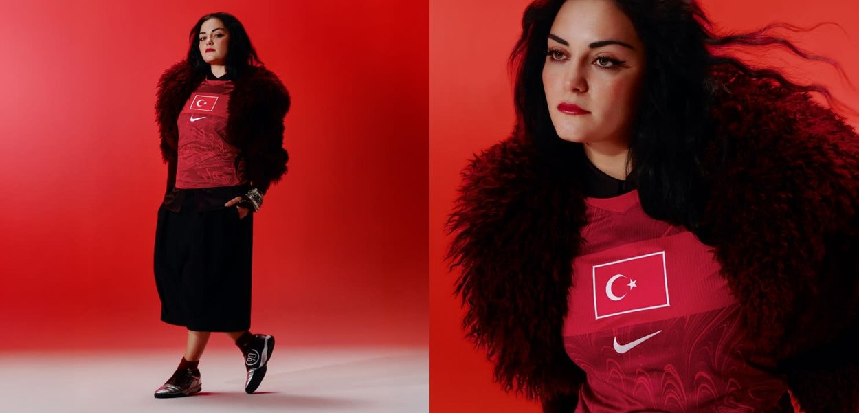 Mujer con el pelo largo y oscuro lleva una camiseta roja de fútbol de Turquía, chaqueta peluda, falda negra y zapatillas, de pie frente a un fondo rojo.