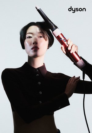 Ferrace per capelli Dyson di colore rosso e nero, con un design cilindrico elegante, punta rosa, pulsanti di controllo e una presa testurizzata.