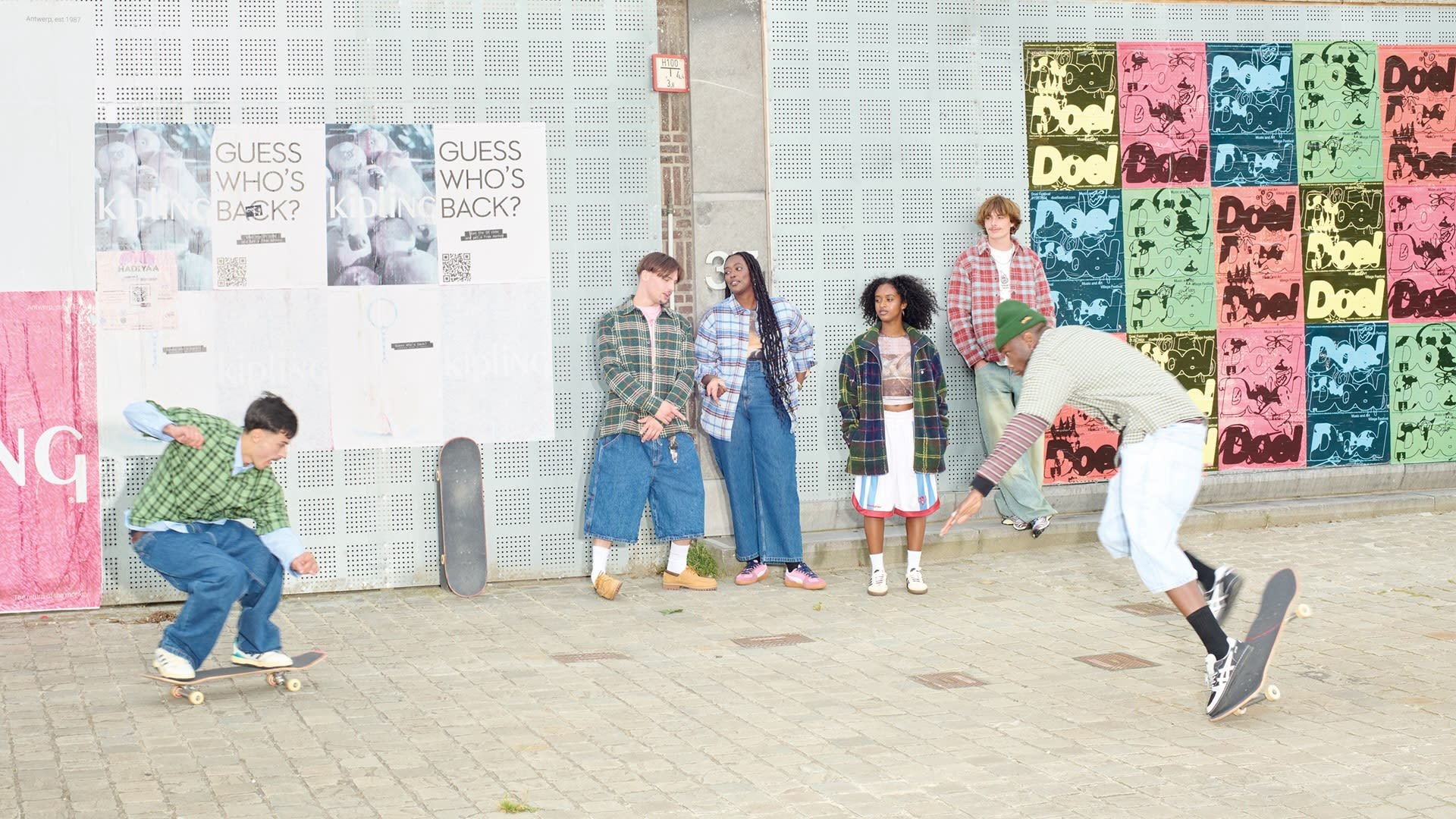 Groep van vijf mensen in geruite overhemden en casual kleding, met skateboards en posters op de achtergrond, in een stedelijke omgeving met een gestructureerde bestrating.