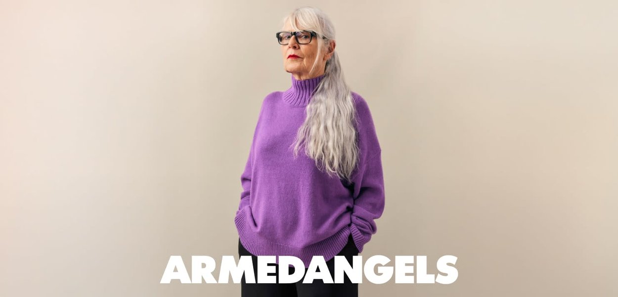Purple knitted sweater with a high ribbed neck, relaxed fit, and dropped shoulders, paired with black pants. Clear background.