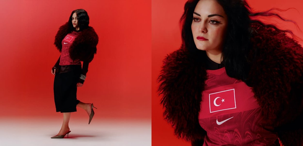 Mujer de pelo largo y oscuro lleva una camiseta de fútbol de Turquía, un chal de piel rojo, falda negra y tacones, posando ante un fondo rojo sólido.