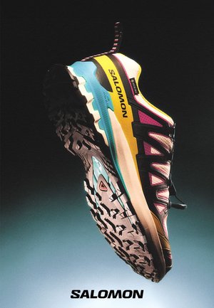 Bunte Salomon Trailschuhe mit einer strukturierten Sohle, die eine Mischung aus Pink, Gelb, Schwarz und türkisfarbenen Akzenten aufweisen. Leichtes Design mit Mesh-Obermaterial.