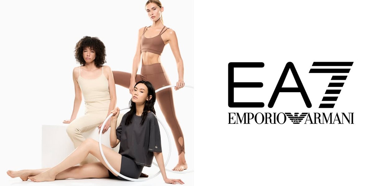 Drie modellen in neutraalgekleurde sportkleding poseren met een fitnesshoepel naast het zwarte EA7 Emporio Armani-logo op een witte achtergrond.