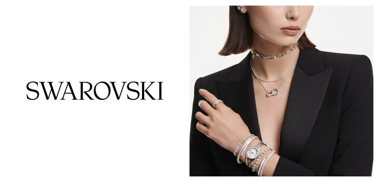 Les bijoux Swarovski présentent un métal argenté dans un design en couches, incluant un collier ras du cou à chaîne épaisse, plusieurs bracelets et une montre.