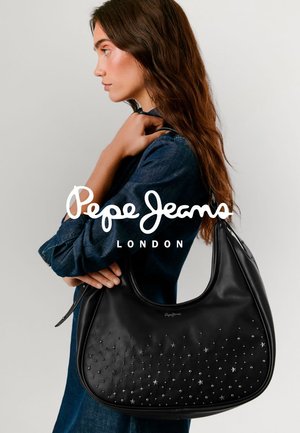 Bolso de cuero negro con adornos en forma de estrella, estilo hobo, textura suave y forma curva. La modelo lleva una blusa de mezclilla y sostiene el bolso.