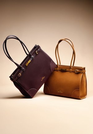 Zwei Handtaschen: eine dunkelviolett, eine beige. Beide bestehen aus glattem Leder, verfügen über zwei Griffe, goldfarbene Hardware-Details und ausgefallene Seitenpanelen.