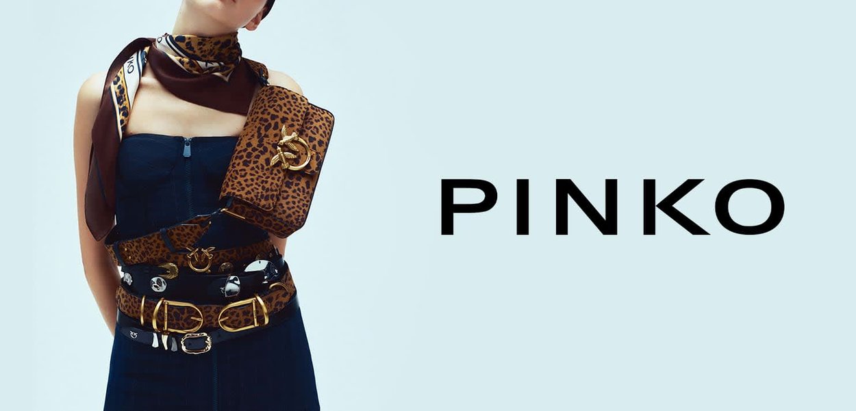 Borsa con stampa leopardata abbinata a cinture nere a strati. Il modello indossa un top blu senza spalline e una sciarpa marrone a motivi, con uno sfondo chiaro.