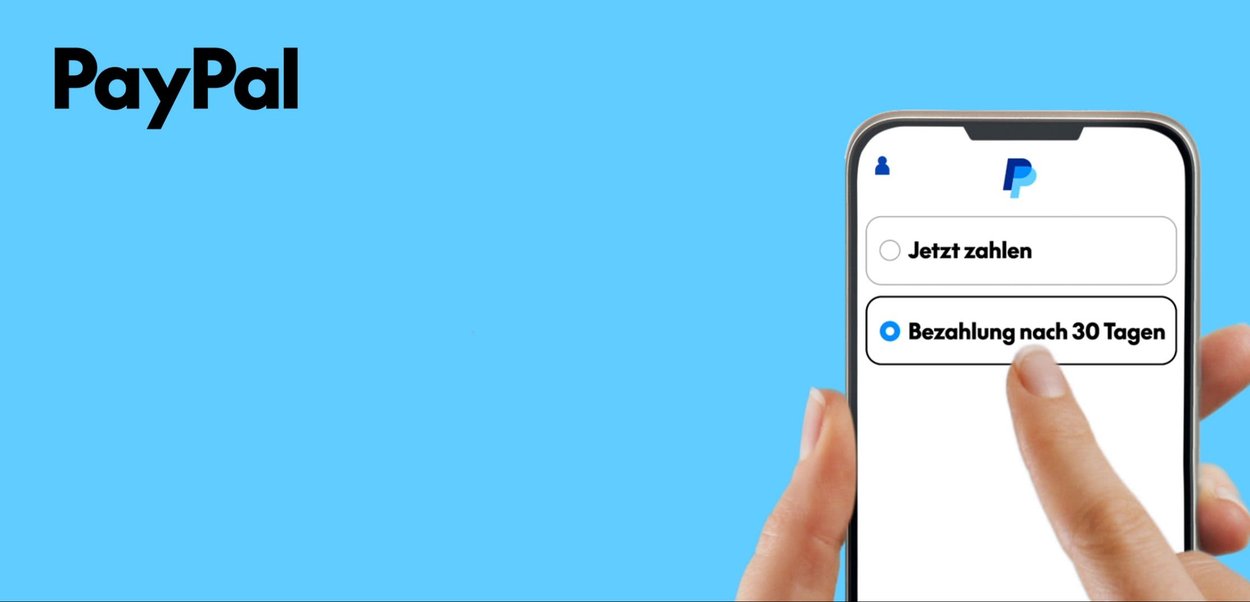 Hand hält Smartphone mit PayPal-App, die Zahlungsoptionen in Deutsch zeigt: "Pay now" und ausgewählt "Pay in 30 days.". Blauer Hintergrund.