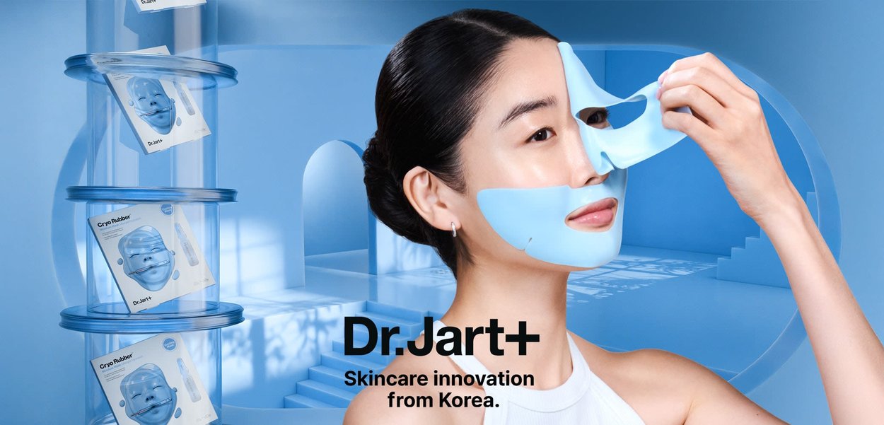 Blue silicone face mask applied on a person's face, featuring cutouts for eyes and mouth. Clear packaging with Dr. Jart+ Cryo Rubber branding.