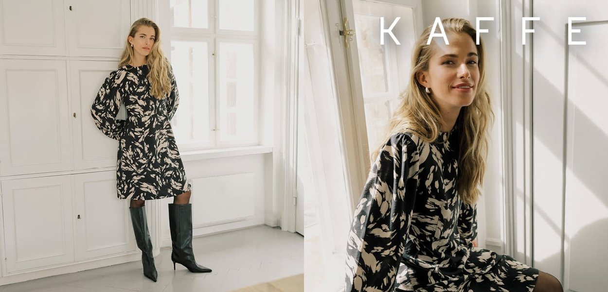 Robe noire avec un motif floral en nuances de rose et de crème. Manches longues et coupe décontractée, associée à des bottes noires montant jusqu'au genou.