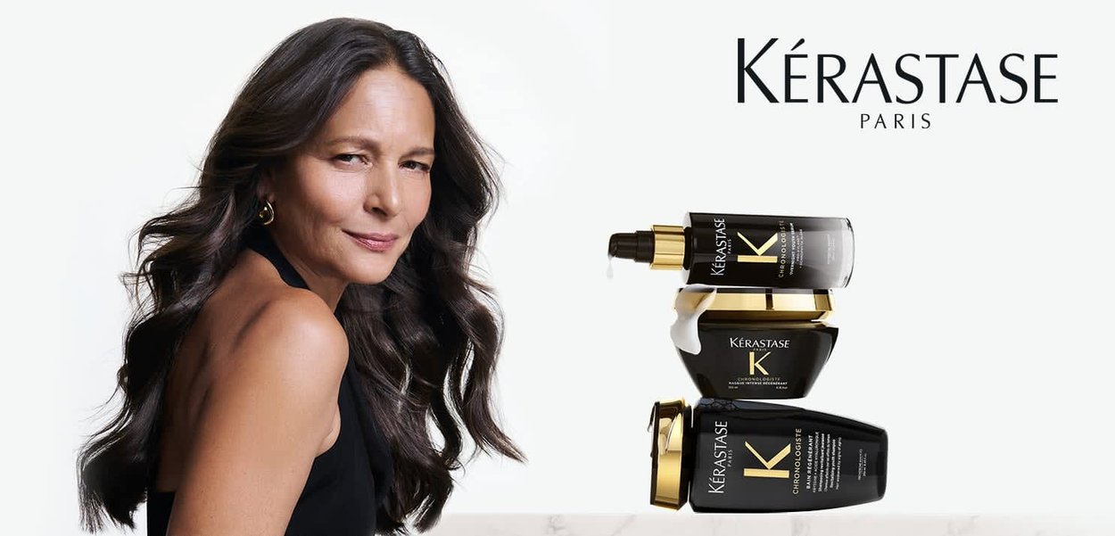 Mujer con cabello largo y oscuro, vestida de negro, junto a tres productos de cuidado capilar Kérastase Paris apilados sobre un fondo blanco.