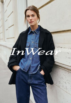 Black overcoat over a denim shirt, paired with dark blue jeans. Smooth fabric textures and classic designs. Neutral background.
