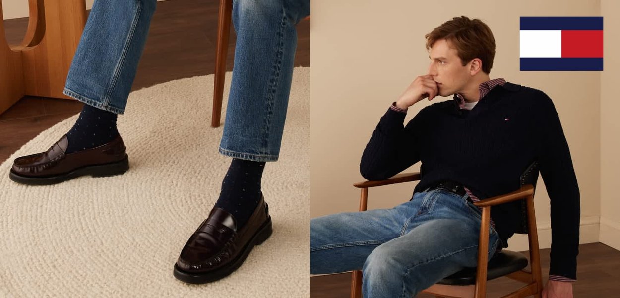 Brune skinnloafers med lav profil, kombinert med blå denimjeans og marineblå sokker med prikker på et teksturert teppe; modellen har på seg en marineblå kabelstrikket genser.