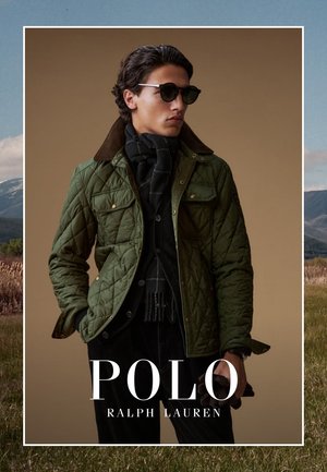 Uomo che indossa una giacca trapuntata verde, una sciarpa nera e occhiali da sole, che tiene dei guanti, con il testo "Polo Ralph Lauren" in basso.