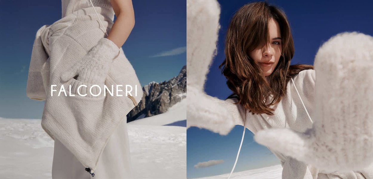 Frau trägt weiße, gestrickte Fäustlinge und eine passende Weste in einer verschneiten Berglandschaft unter einem klaren blauen Himmel.