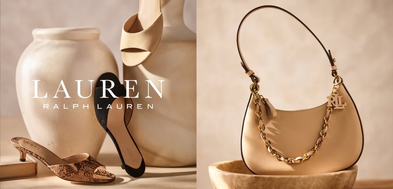 Zapatos de tacón altos beige y negros exhibidos junto a grandes jarrones de cerámica y un bolso beige con cadena dorada y adorno con logo sobre un fondo neutro.