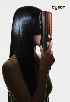 Piastra per capelli Dyson tenuta verticalmente, con un corpo nero elegante e dettagli in rame. I capelli lunghi e lucenti dell'utente hanno un taglio netto.