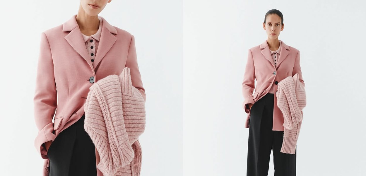 Rosa Blazer mit strukturiertem Kragen und einem einzelnen Knopf, kombiniert mit einem hellrosa gestrickten Schal. Das Modell trägt schwarze Hosen.