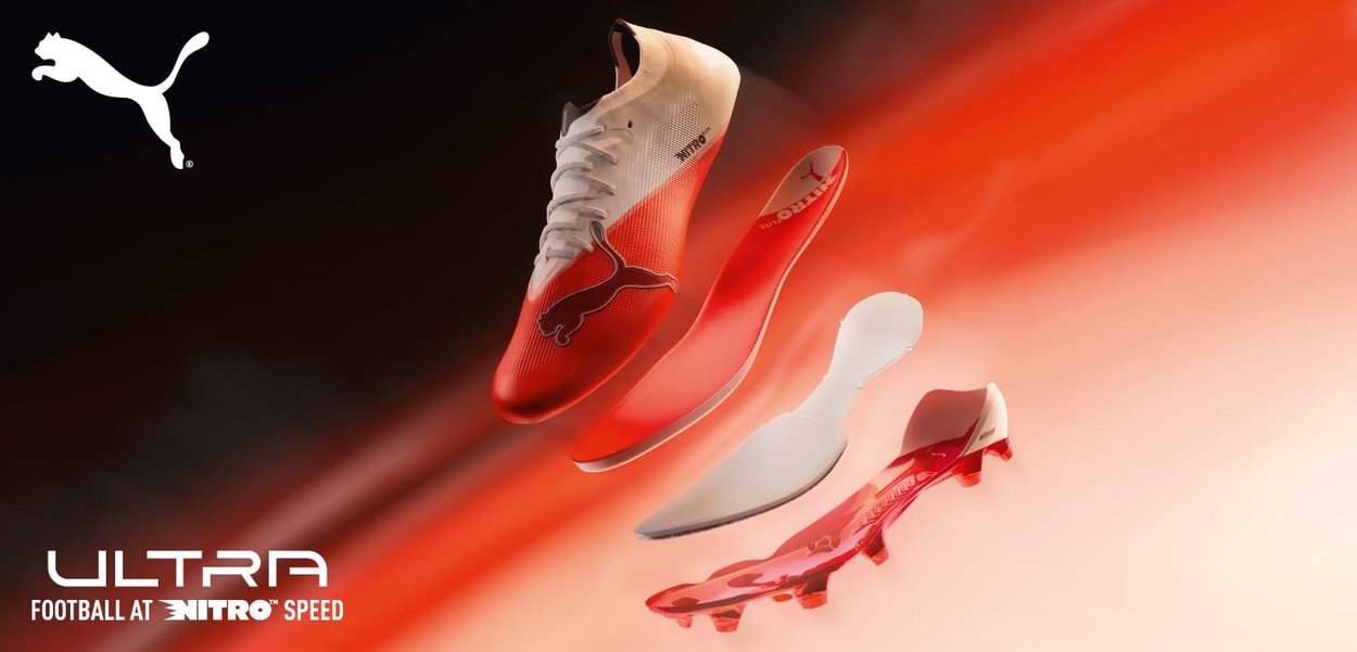 Bota de fútbol Puma roja y blanca con componentes separados de plantilla, entresuela y suela que flotan contra un fondo degradado rojo y blanco.