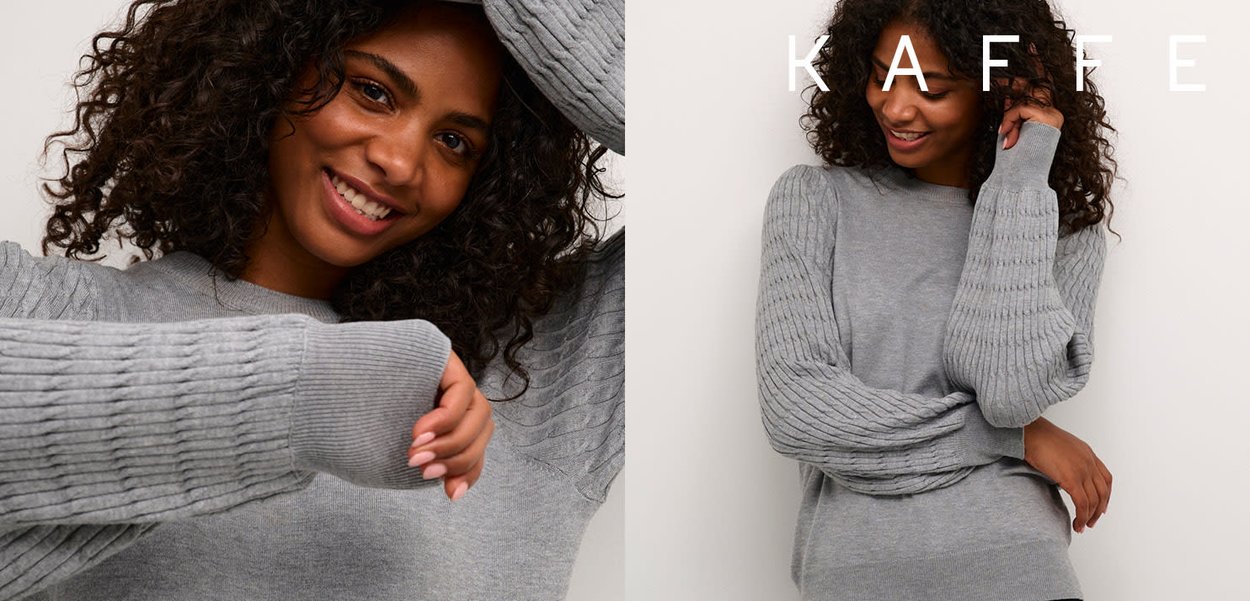 Grå stickad tröja med ribbade ärmar och avslappnad passform. Mjuk textur med en rund halsringning. Modell som visar en lekfull pose.