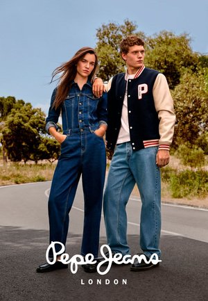 Zwei Models stehen auf einer Straße mit Bäumen im Hintergrund und tragen lässige Denim-Outfits; eines trägt eine Jacke mit einem "P"-Aufnäher.