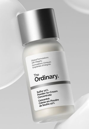 Glass bottle of The Ordinary Sulfur 10% Powder-to-Cream Concentrate with silver cap on a white background.