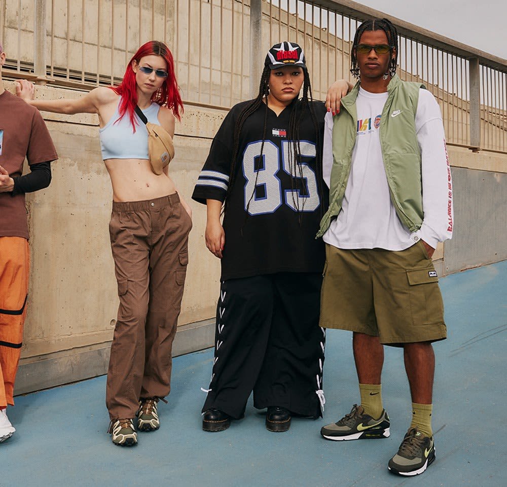 Quatre personnes à l'extérieur : un top court bleu clair, un pantalon cargo marron, un jersey ample noir, un gilet vert et un short. Divers styles de chaussures.