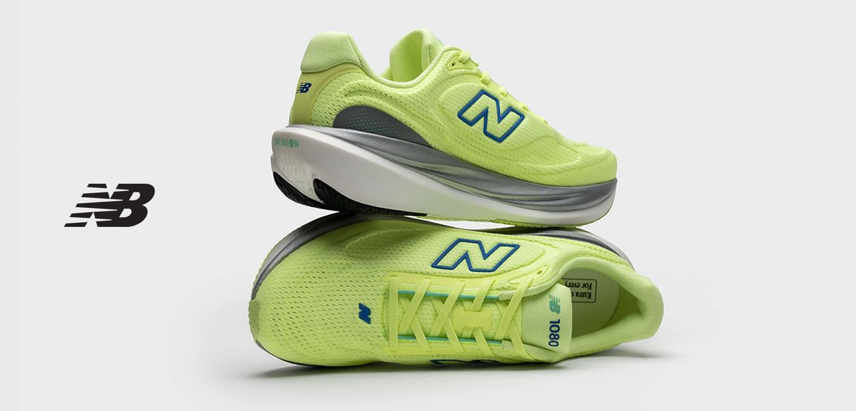 Persona con pantalones cortos color burdeos sostiene un zapato de correr New Balance de color amarillo neón por el talón, con los cordones colgando.