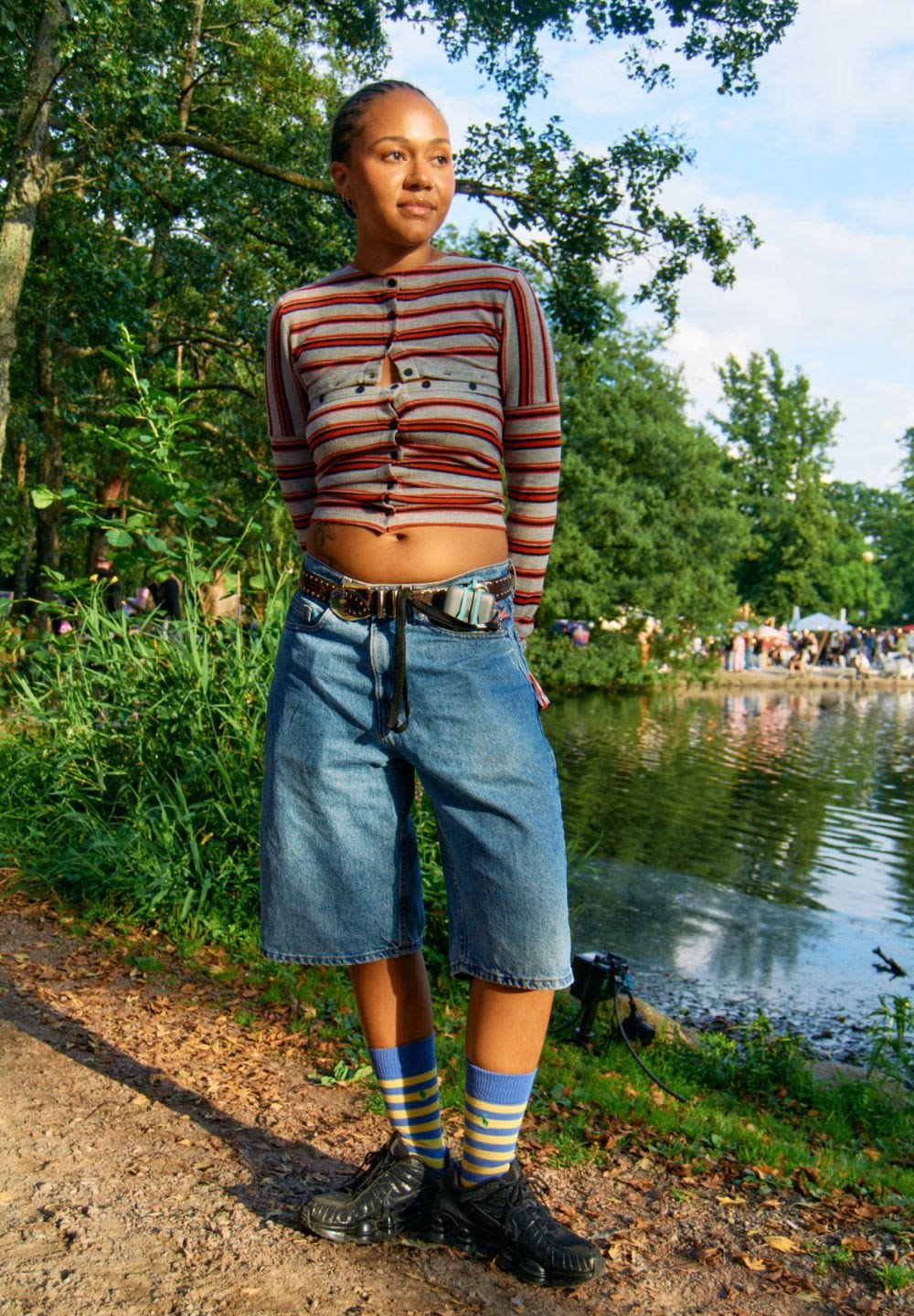 Randig kort cardigan, blå denimshorts, svarta sneakers och blårandiga strumpor. Anmärkningsvärda detaljer: knappar på cardiganen och bälte-accessoarer.
