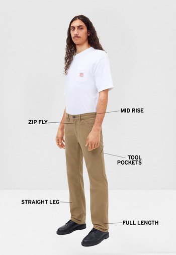 Pantalones beige de largo completo con pierna recta, ajuste de talle medio, bragueta con cremallera y múltiples bolsillos para herramientas. Combinados con una camisa blanca de manga corta.