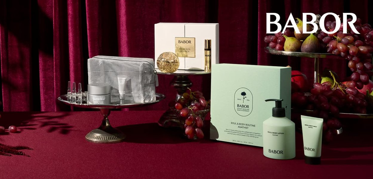 Colección de cuidado de la piel Babor en una bandeja plateada: frasco gris, ampollas transparentes, dispensador de loción verde y caja con texto, todo sobre un fondo rojo intenso.