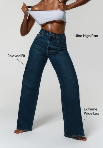 Jeans de mezclilla oscura de corte alto con un ajuste relajado y pierna extremadamente ancha. Las características incluyen una cinturilla distintiva y una textura suave.