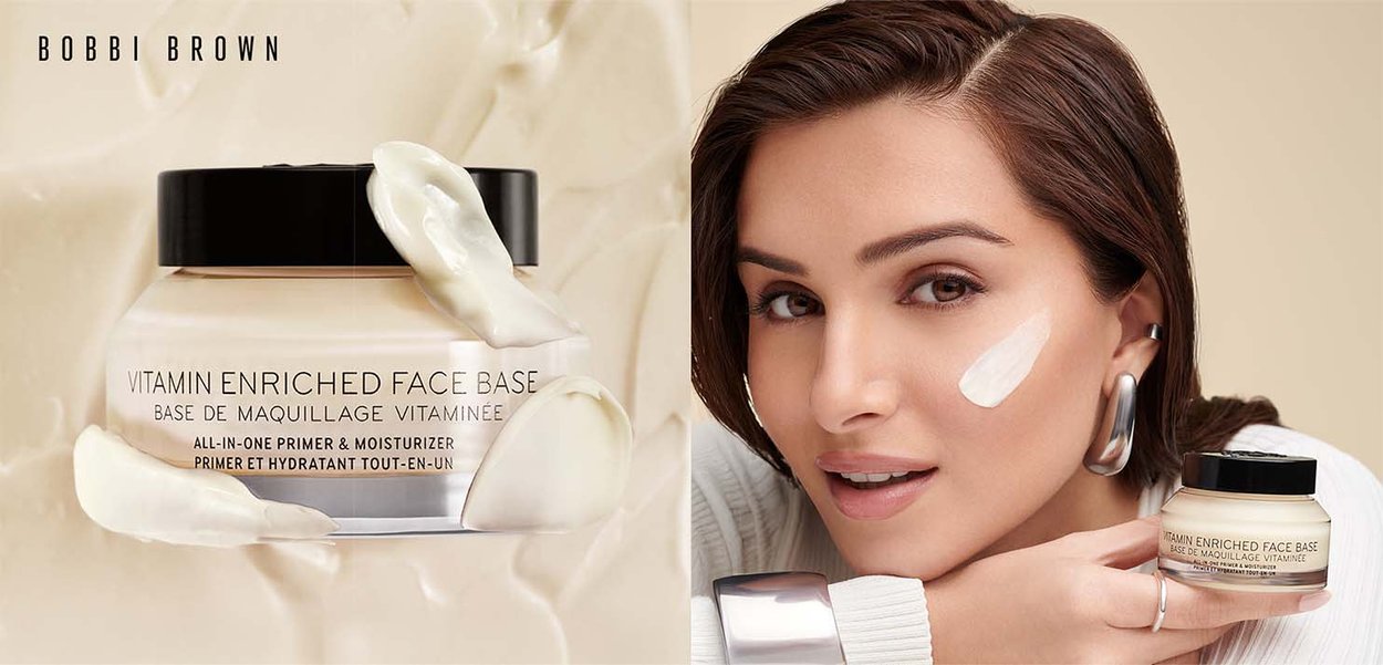 Jar de base de visage enrichie en vitamines avec de la crème sur fond beige, et une femme avec une touche de crème sur la joue tenant le pot, portant des boucles d'oreilles en argent.