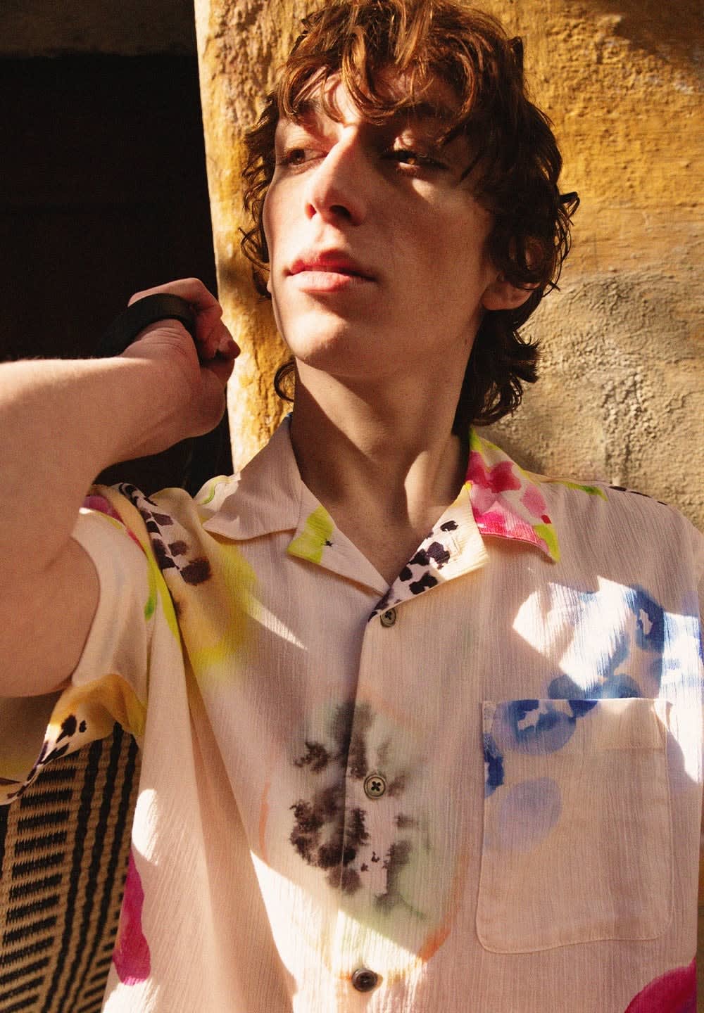 Camicia a maniche corte con colletto in un tessuto leggero. Presenta un motivo astratto multicolore con spruzzi di rosa, blu, giallo e nero.