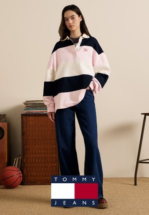 Prześwitująca różowo-granatowo-kremowa koszulka rugby z kołnierzykiem i długimi rękawami, zestawiona z szerokimi dżinsami o szerokich nogawkach. Płaskie, teksturowane powierzchnie.