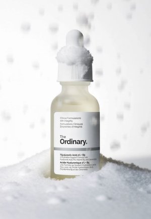 Flacon compte-gouttes du sérum The Ordinary Acide Hyaluronique 2% + B5 entouré de mousse blanche ou de bulles.