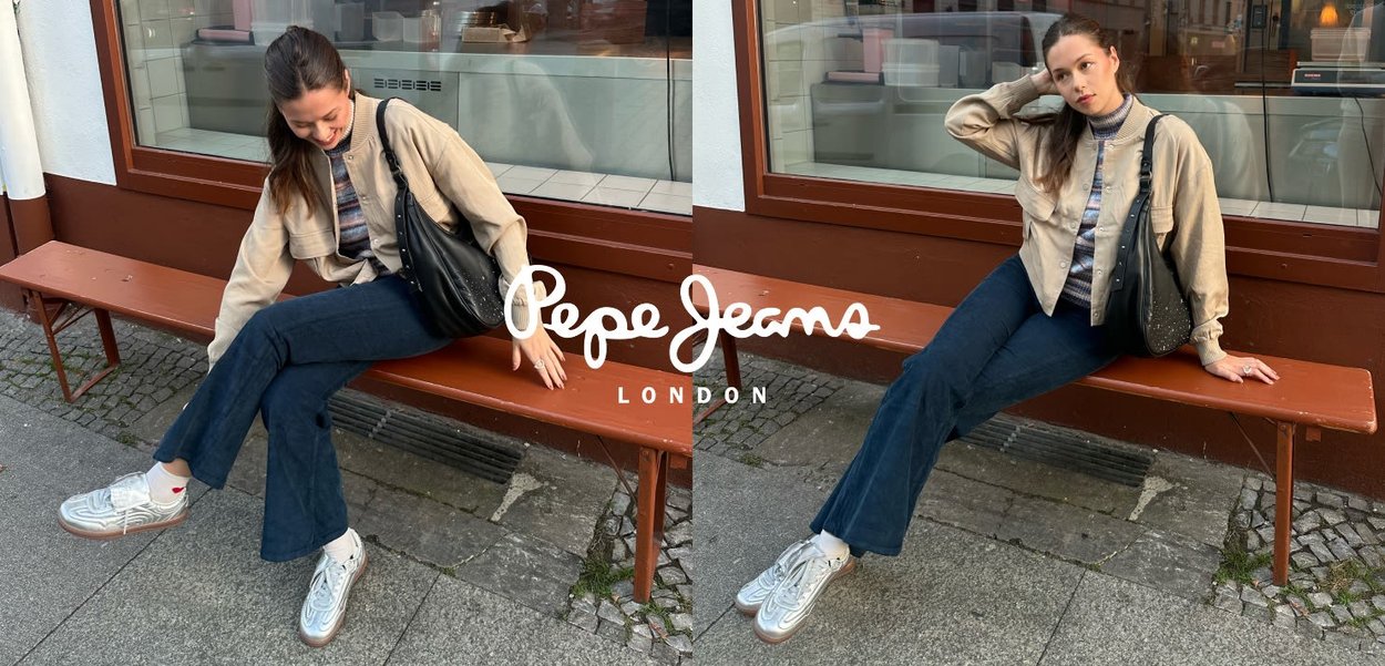 Beige bomberjack, gestreept top, donkergroene flared jeans, zilveren sneakers met rode accenten en een zwarte tas met glitters, zittend op een bankje.