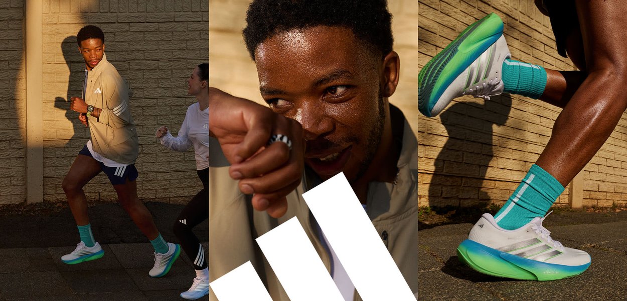 Twee atleten die glimlachen en vooruit wijzen terwijl ze op een verhard pad buiten staan, met groen en een stenen muur op de achtergrond.