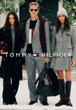 Trzy modelki stoją na śniegu, ubrane w dopasowane, w kratę stroje. Akcesoria to czarna torba, szara czapka i kozaki do kolan.