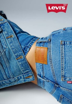 Jeans in denim in einem hellen Blau mit einem verblassten Muster, ausgestattet mit einem braunen Lederpatch auf der Rückseite und dezenten Steppnähten.