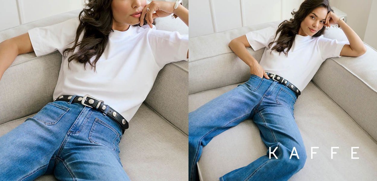 Weißes Kurzarmshirt kombiniert mit hochtaillierten blauen Jeans und einem schwarzen Gürtel mit silbernem Nieten, auf einem hellgrauen Sofa präsentiert.