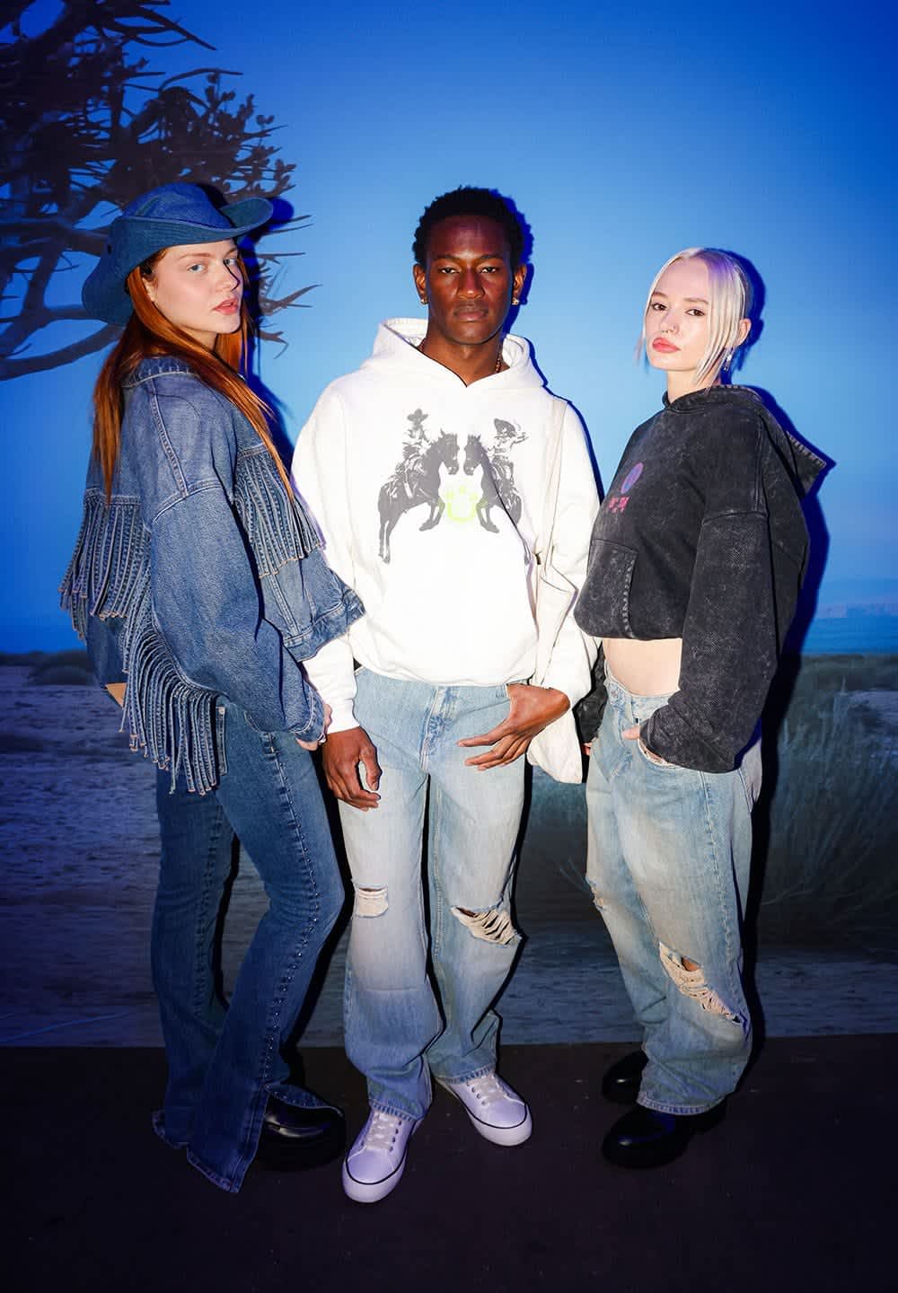 Three individuals stand together against a blue background. They wear frayed denim jackets, hoodies, and distressed jeans, showcasing various textures.