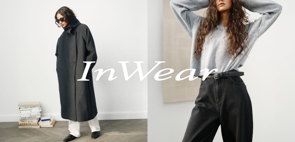 Gray wool coat with a high collar and pockets, paired with a light gray knit sweater and black high-waisted trousers. Black loafers.