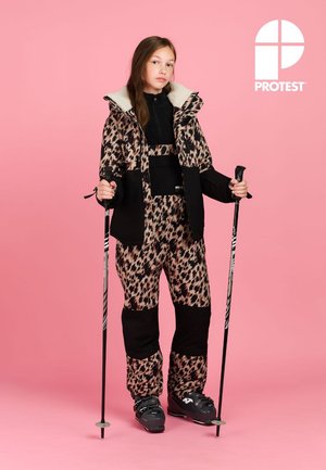 Ski-outfit met luipaardprint, voorzien van een zwarte thermische laag, een witte nepbonten kraag en zwarte accenten. Ski-stokken in de handen, tegen een roze achtergrond.