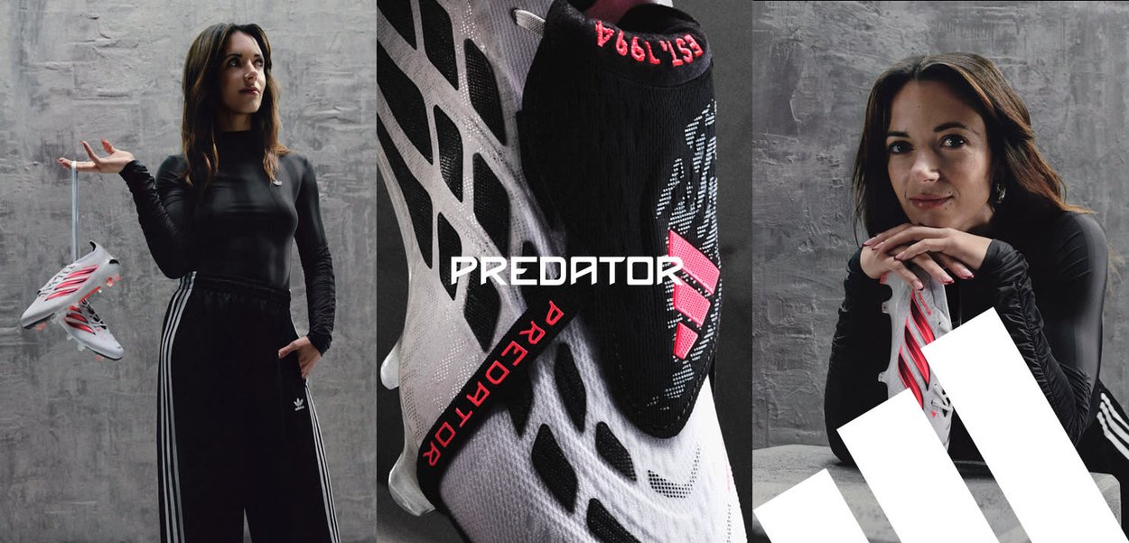 Kobieta w czarnym stroju sportowym trzyma białe i różowe korki piłkarskie Adidas Predator na tle szarej, teksturowanej ściany.