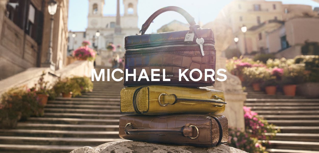 Trois sacs à main empilés en cuir marron, jaune et marron foncé, présentant des finitions texturées et des fermetures éclair argentées, avec un marquage visible.